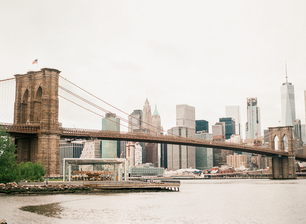 The Brooklyn Bridge and Lower Manhattan, including the Freedom Tower, taken from Brooklyn Bridge Park during NYC engagement photos by You Look Lovely Photography