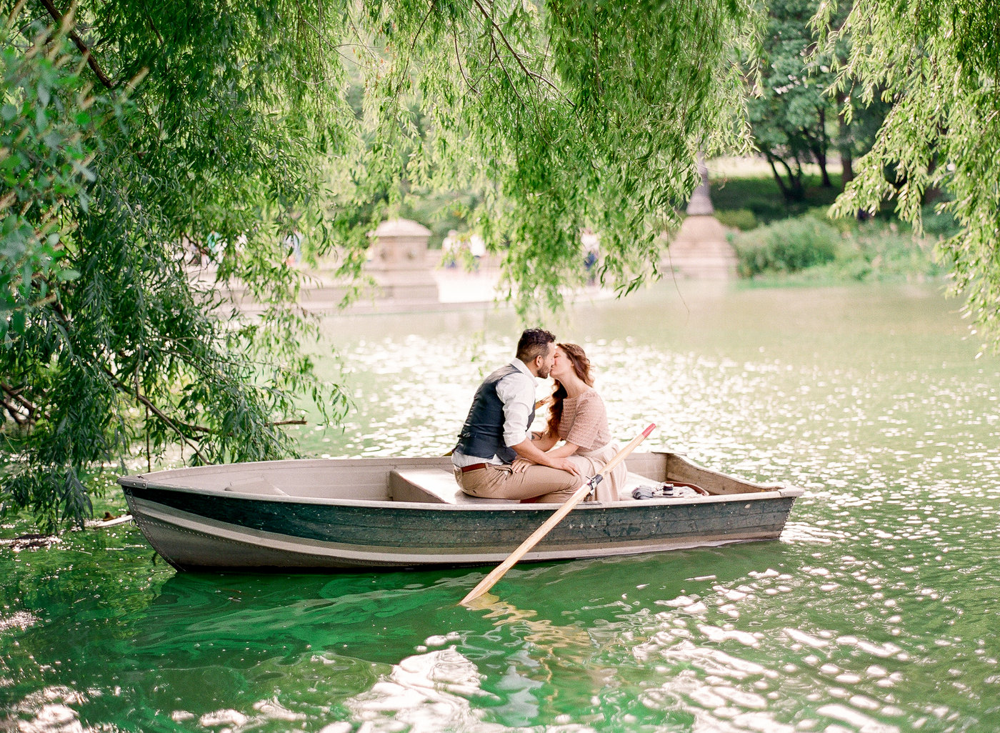 A couple kissing in a rowboat on the lake at Central Park under a weeping willow tree during an algae bloom that turned the water green photographed You Look Lovely Photography