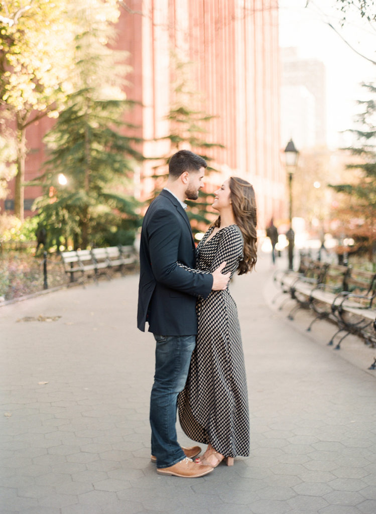A couple embracing during romantic NYC engagement photos with You Look Lovely Photography at Washington Square Park