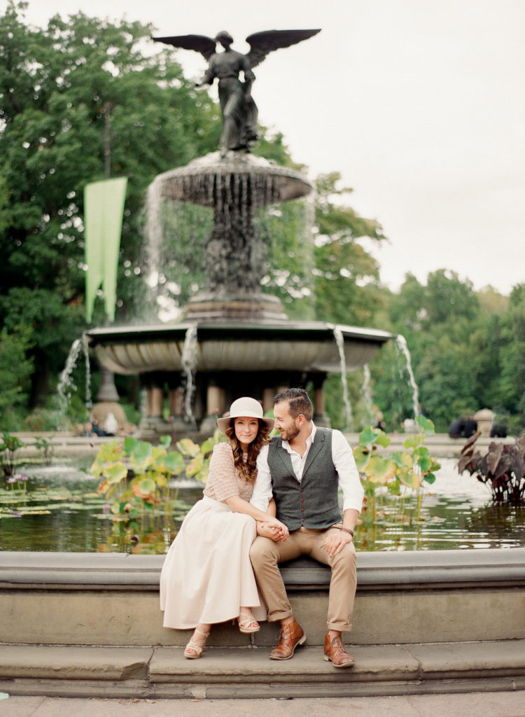 A couple sitting on the edge of Bethesda Fountain in Central Park during NYC engagement photos with You Look Lovely Photography