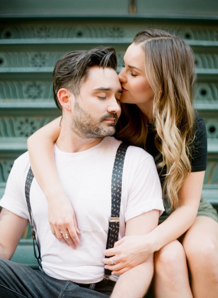 A young stylish couple kissing on a green staircase in SoHo during NYC engagement photos