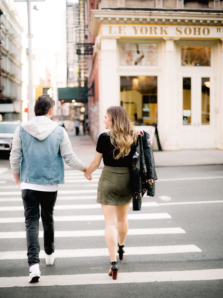 A young stylish couple crossing the street in SoHo during NYC engagement photos by You Look Lovely Photography