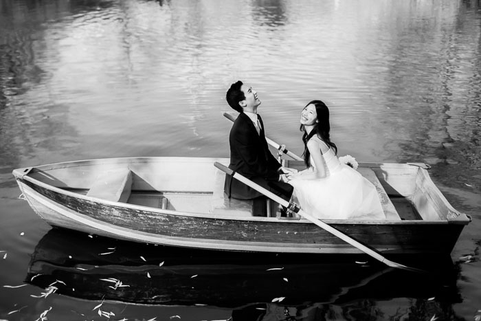 A well-dressed couple laughing in love in a rowboat on the lake at Central Park during romantic engagement photos by You Look Lovely Photography