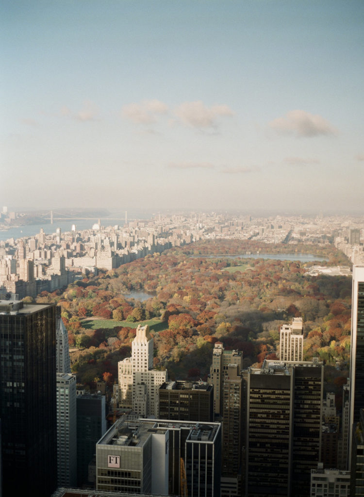 A spectacular aerial image of New York City looking north from the roof at Top of the Rock showing Central Park in the fall with colorful foliage, with the Upper West Side, Harlem, and the George Washington Bridge in the distance photographed by You Look Lovely Photography