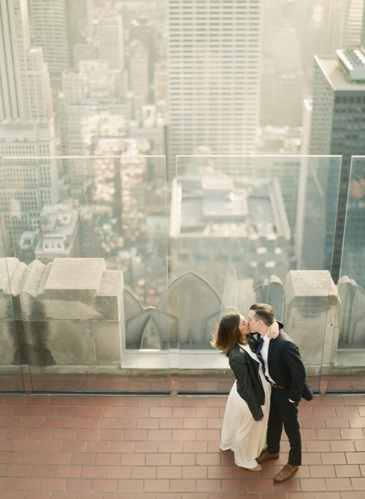 An aerial image of a couple kissing with the city behind them during their Top of the Rock engagement session with You Look Lovely Photography