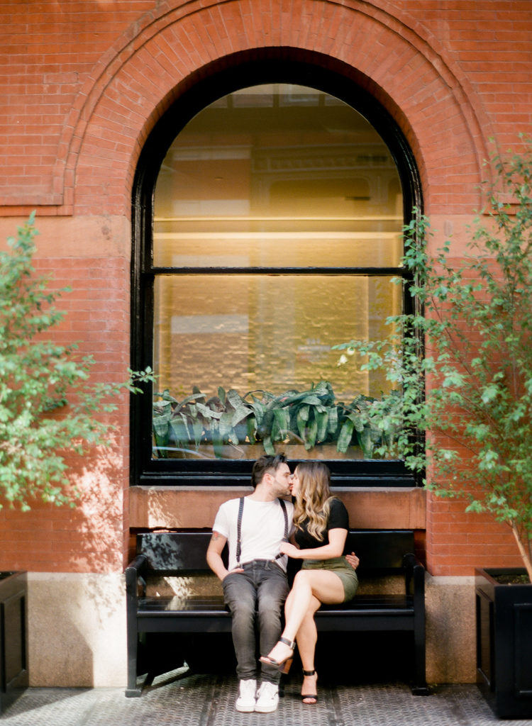 A couple kissing on a bench in Soho for their NYC editorial engagement photos with You Look Lovely Photography