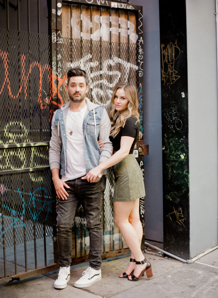 A stylish couple pose in front of graffiti art for their SoHo street engagement photos with You Look Lovely Photography
