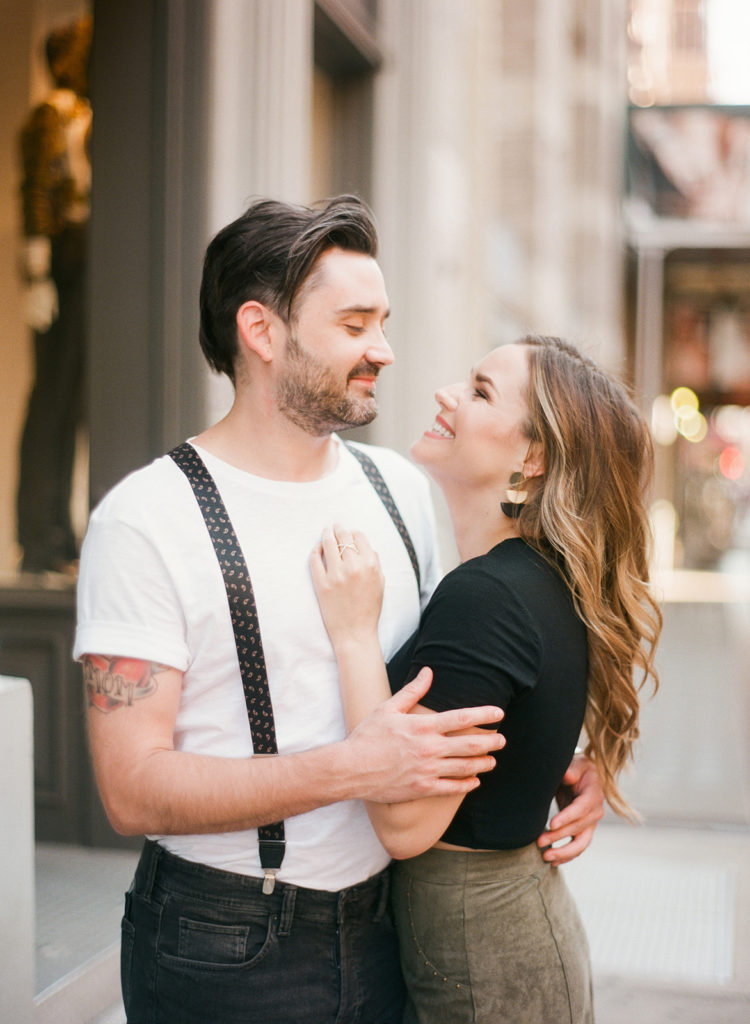 A couple in love, smiling and embracing on the stylish streets of Soho NYC during their engagement session with You Look Lovely Photography