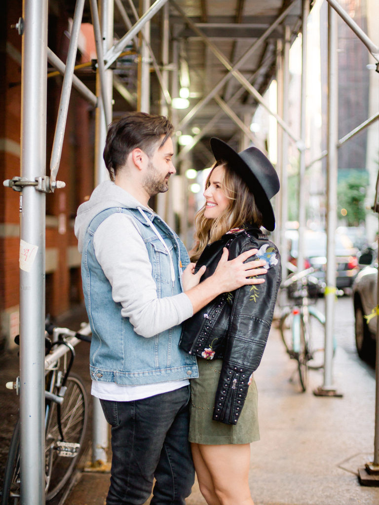 A fashionable couple get close during their SoHo city streets engagement photos with You Look Lovely Photography