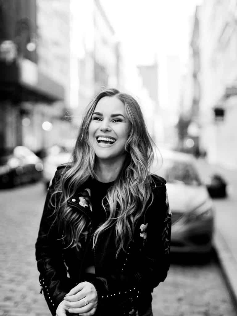 A candid moment of a lovely laughing woman on the cobblestone streets of SoHo NYC during her editorial engagement session with You Look Lovely Photography