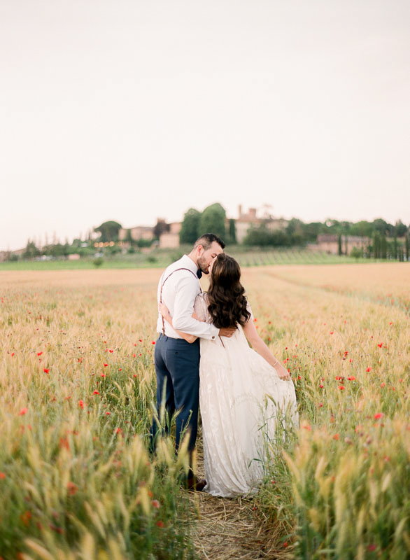 A destination wedding couple sharing a sweet moment in a Tuscan field across from a Tuscan Villa photographed by You Look Lovely Photography