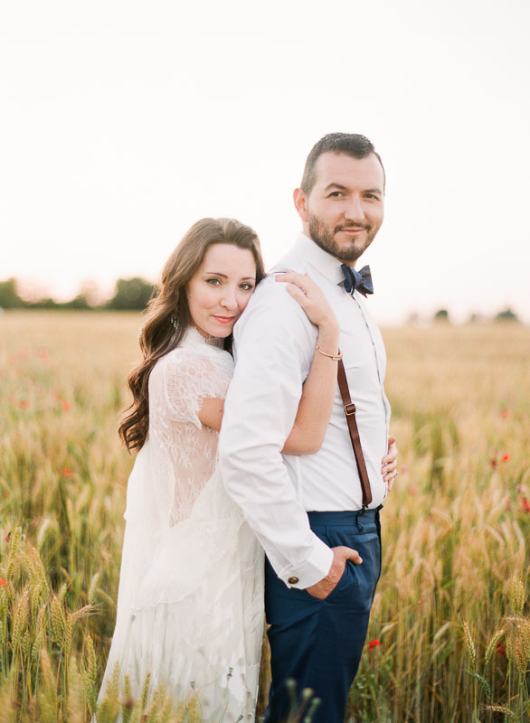 A newlywed couple embrace in a poppy field in Tuscany for their wedding portraits photographed by You Look Lovely Photography