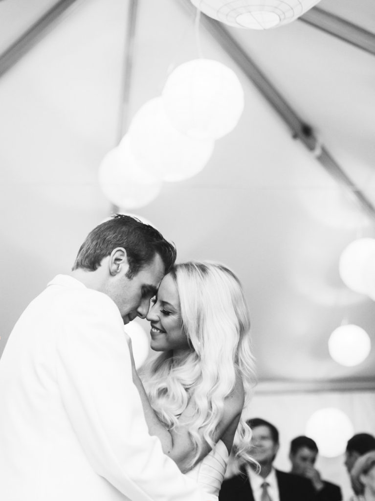 Black and white image of a bride and groom cuddling close during their first dance photographed by You Look Lovely Photography